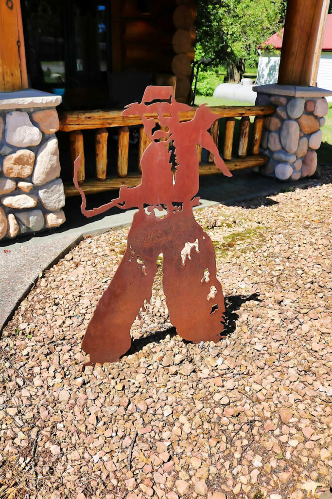 Yellowstone Log Homes metal cowboy located outside the McGregor office 4417